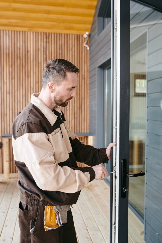 Young repairman fixing lock in large transparent door